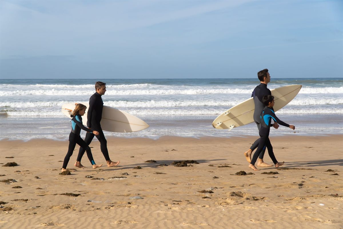 A family walking to the beach with surfboards in Taghazout, Morocco