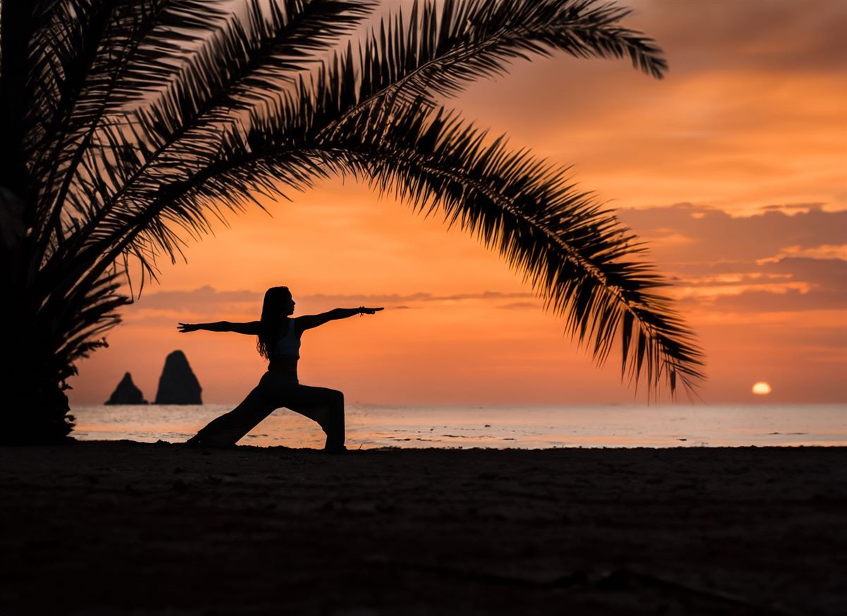 A woman practising yoga on the beach at sunrise in Taghazout, Morocco